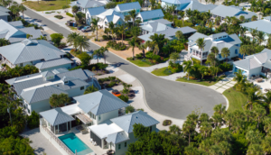 Aerial view of a residential neighborhood in Florida featuring houses with metal roofs, palm trees, and a curved street, illustrating potential areas affected by storm damage relevant to insurance claims.